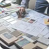 テーブルの上に建築図面と多数の素材サンプルが並べられた設計・デザインの作業風景