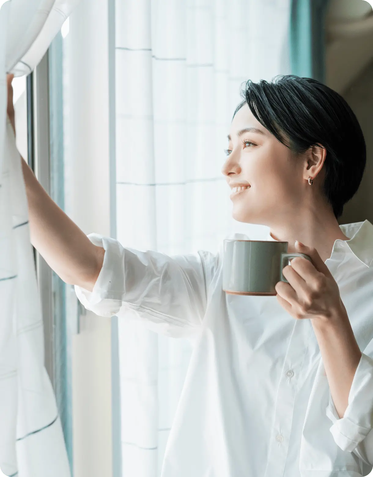 カーテンを開けて微笑む女性とコーヒーカップ